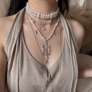 Close-up of layered baroque pearl necklace with sparkling diamond-set cross pendants