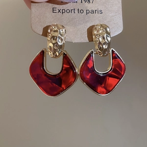 Detail of vintage acrylic drop earrings with red resin and gold hammered metal texture
