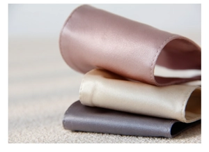 Detailed stack of silk sleep masks in dusty pink, champagne, and dark gray shades