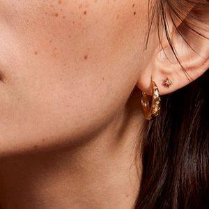 Close-up of model wearing S925 sterling silver gold hoop earrings with star shaped crystals