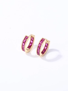 Detalle de pendientes de aro dorados con circonitas rojo rosa de corte cuadrado