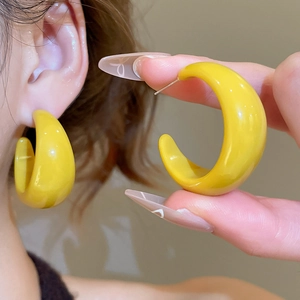 Détail des boucles d'oreilles créoles C en résine jaune portées et présentées