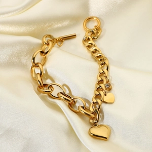 Dettaglio del bracciale a catena placcato oro 18K con ciondoli a cuore su sfondo di seta