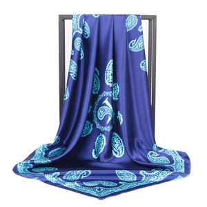 Detail showing the elegant drape and glossy paisley pattern of the blue silk scarf