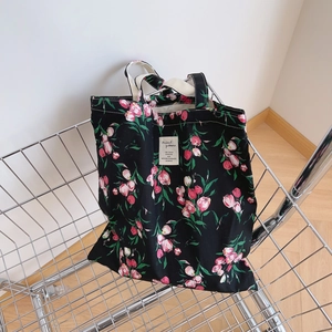 Floral canvas tote bag with pink tulip patterns in a stainless steel shopping basket