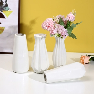 Modern white ceramic vases set with different shapes displayed against a yellow wall background