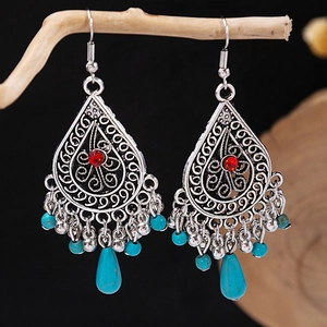 Detail of bohemian drop earrings with turquoise beads on a rustic wooden branch