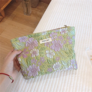 Close-up of quilted floral cosmetic bag with simple wish label and zipper closure