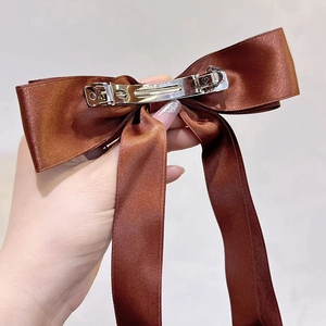 Detailed back view of a brown satin bow hair clip with silver metal spring fastener