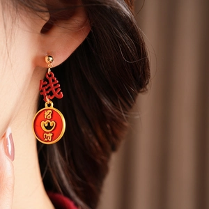 Detailed view of vintage gold enamel earrings with lucky Chinese characters on a model