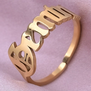 Macro shot of gold stainless steel ring with Gothic Beautiful word carving on silk fabric
