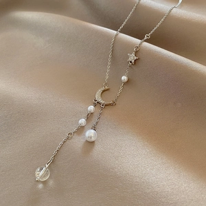 Long titanium steel necklace with moon star pendants and pearls on silk background