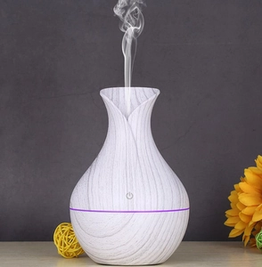 Detail of wood grain aromatherapy diffuser with purple light emitting mist on a desk