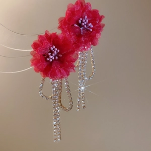 Macro detail of red fabric flower earrings with sparkling rhinestone tassel chain fringes