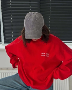 Detail of red crewneck sweatshirt featuring white letter embroidery and casual styling