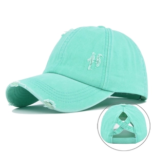 Detail of mint green washed cotton baseball cap featuring elastic ponytail hole and distressed edges