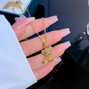 Close-up of golden bear pendant with pavé crystals held by hand over a jewelry box