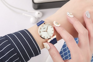 Montre à bracelet magnétique bleu et boîtier or rose portée au poignet d'un mannequin