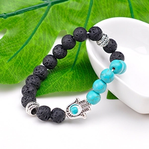 Lava stone and turquoise Hamsa Hand beaded bracelet on a green leaf and ceramic plate