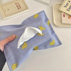 Close-up of purple fabric tissue case with yellow banana patterns held by a hand