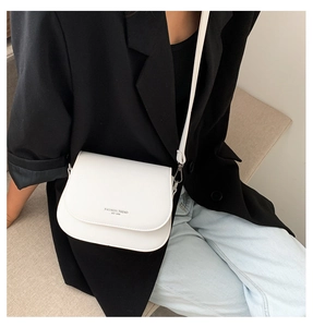 Dettaglio della borsa a tracolla in pelle bianca abbinata a un moderno blazer nero