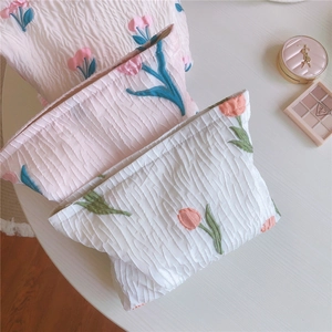 Détail de trousses à cosmétiques en tissu avec broderie de tulipes et texture plissée