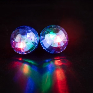 Close-up of 70s retro disco ball earrings with colorful LED lights reflecting on a black surface