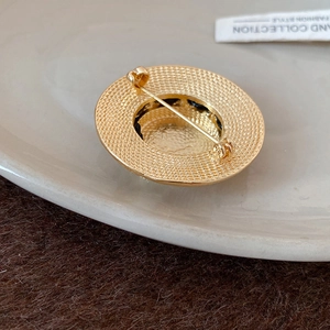 Detailansicht der Rückseite der goldenen Strohhut-Brosche mit feiner Metallstruktur