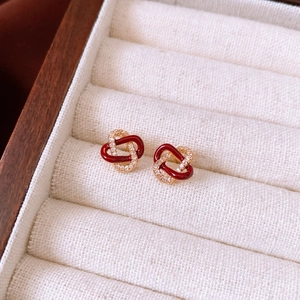 Detailed view of red enamel and zircon earrings on a velvet display stand