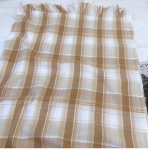 Detailed close-up of brown and beige plaid scarf with soft fringe and woven texture