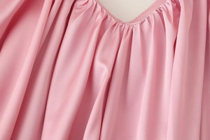 Dettaglio dello scollo dell'abito rosa con design a pieghe e cuciture rifinite