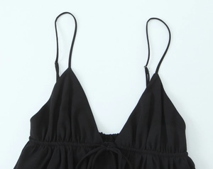 Detail of black V-neck camisole featuring thin straps and pleated drawstring front tie