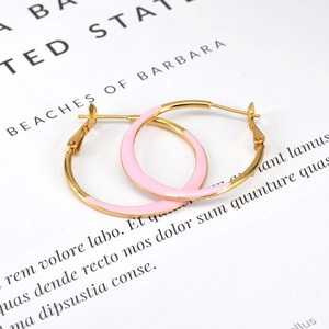 Macro detail of large gold-tone hoops with pink enamel finish on white display card