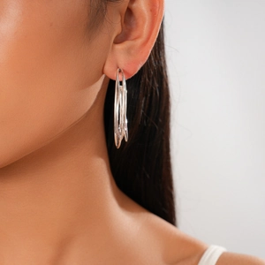 Close-up of silver multilayer geometric C-shaped hoop earrings on a model's ear