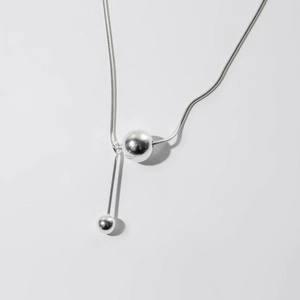 Detail view of silver snake chain necklace with geometric ball and cylinder pendants
