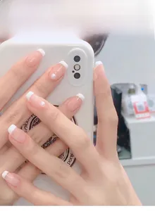 Detailed close-up of French tip press-on nails with white edges and elegant pearl accents