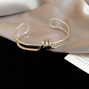 Detail of twisted silver knot bangle on elegant grey silk and velvet background