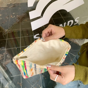 Detail showing inner beige lining and spacious interior of colorful striped canvas pouch