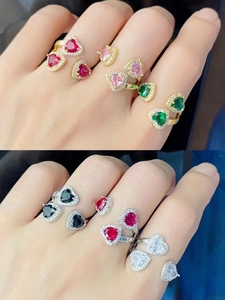 Dettaglio di vari anelli a cuore con zirconi colorati sulla mano con placcatura in oro