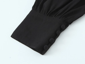 Détail de manche de chemise noire vintage avec poignets plissés et quatre boutons en tissu