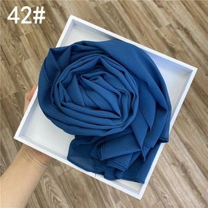 Détail de l'écharpe hijab en mousseline bleu foncé pailletée d'or pliée en rose