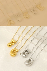 Macro detail of 18K gold and silver bubble letter pendants on fine chain necklaces