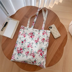 Flat lay detail of a floral cotton tote bag with tulip patterns on a wooden table