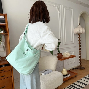 Dettaglio della borsa a tracolla in tela verde menta con coulisse e tasche su modella