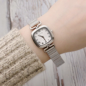 Silver square quartz watch with Roman numerals and metal elastic band on wrist