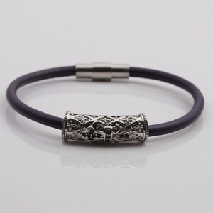 Detail of purple braided leather bracelet with silver magnetic clasp and hollow carvings