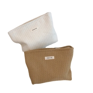 Minimalist woven texture makeup bags in cream and tan colors with simple wish label