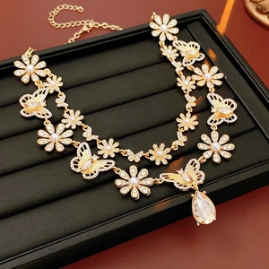 Détail du collier vintage doré avec papillon, perles et pendentif cristal en goutte