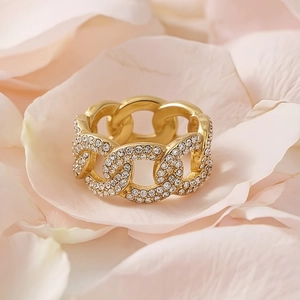 Golden Cuban link chain ring with sparkling crystals on a bed of soft rose petals