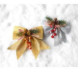 Detail of glitter Christmas bows with pine cones and red berries on a snowy background